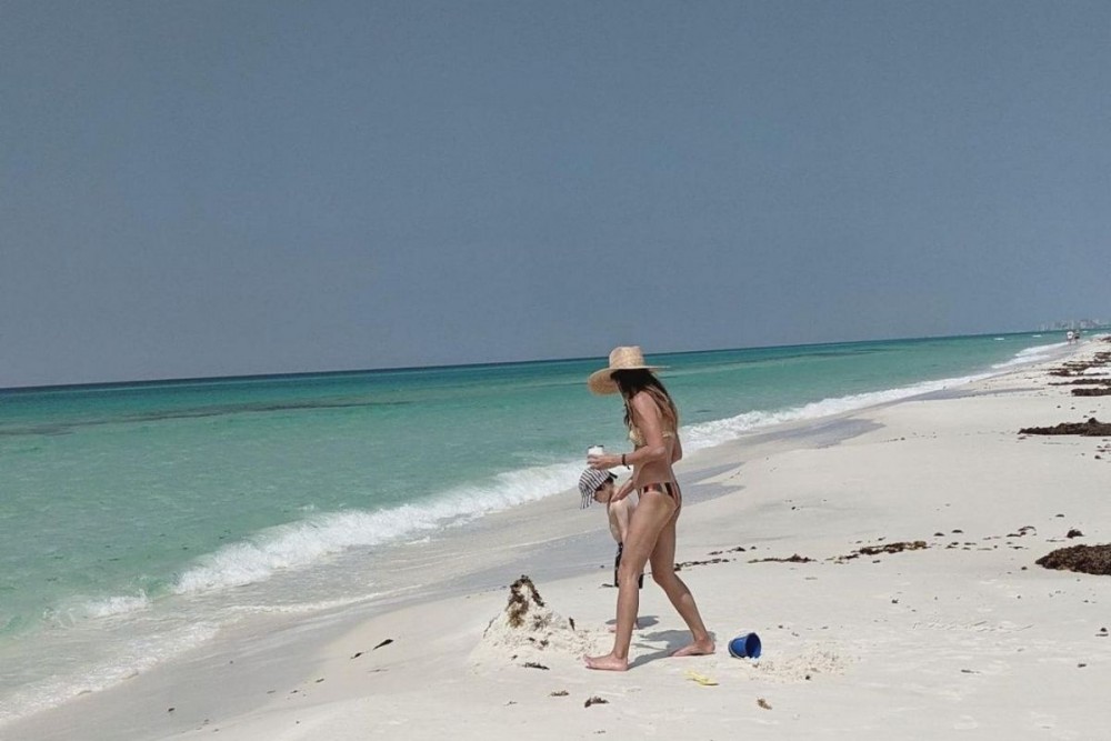 woman and her child on blue mountain beach making a sand castle