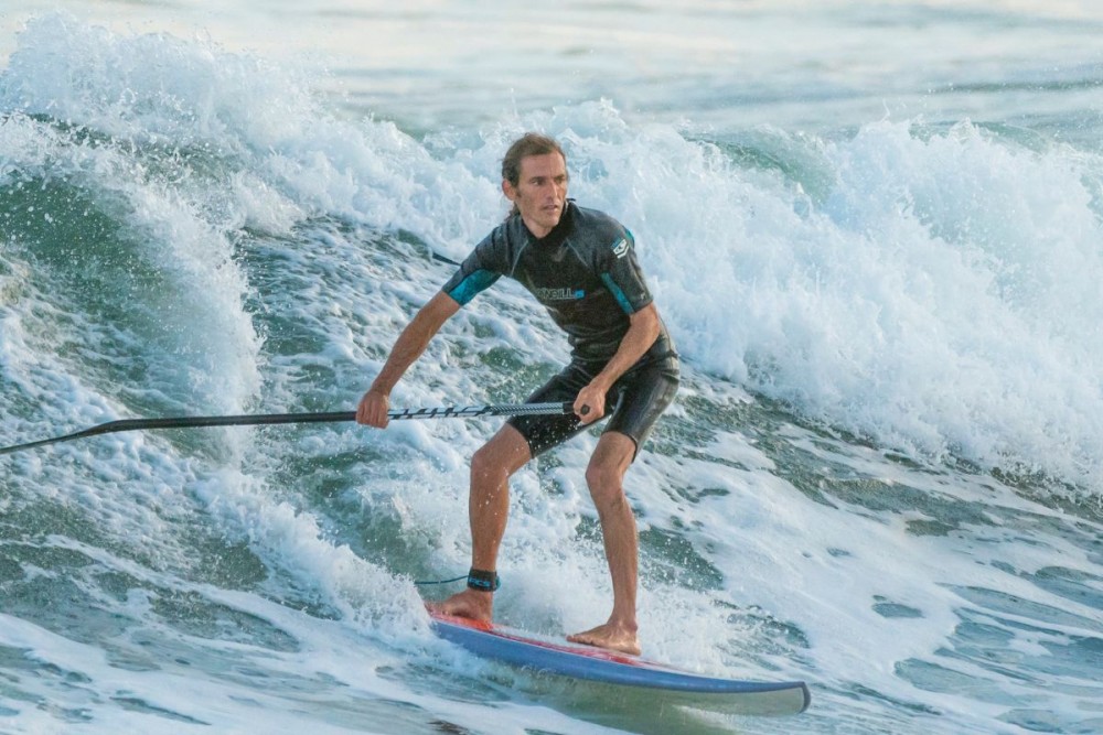 a man Stand-Up Paddleboarding on a wave